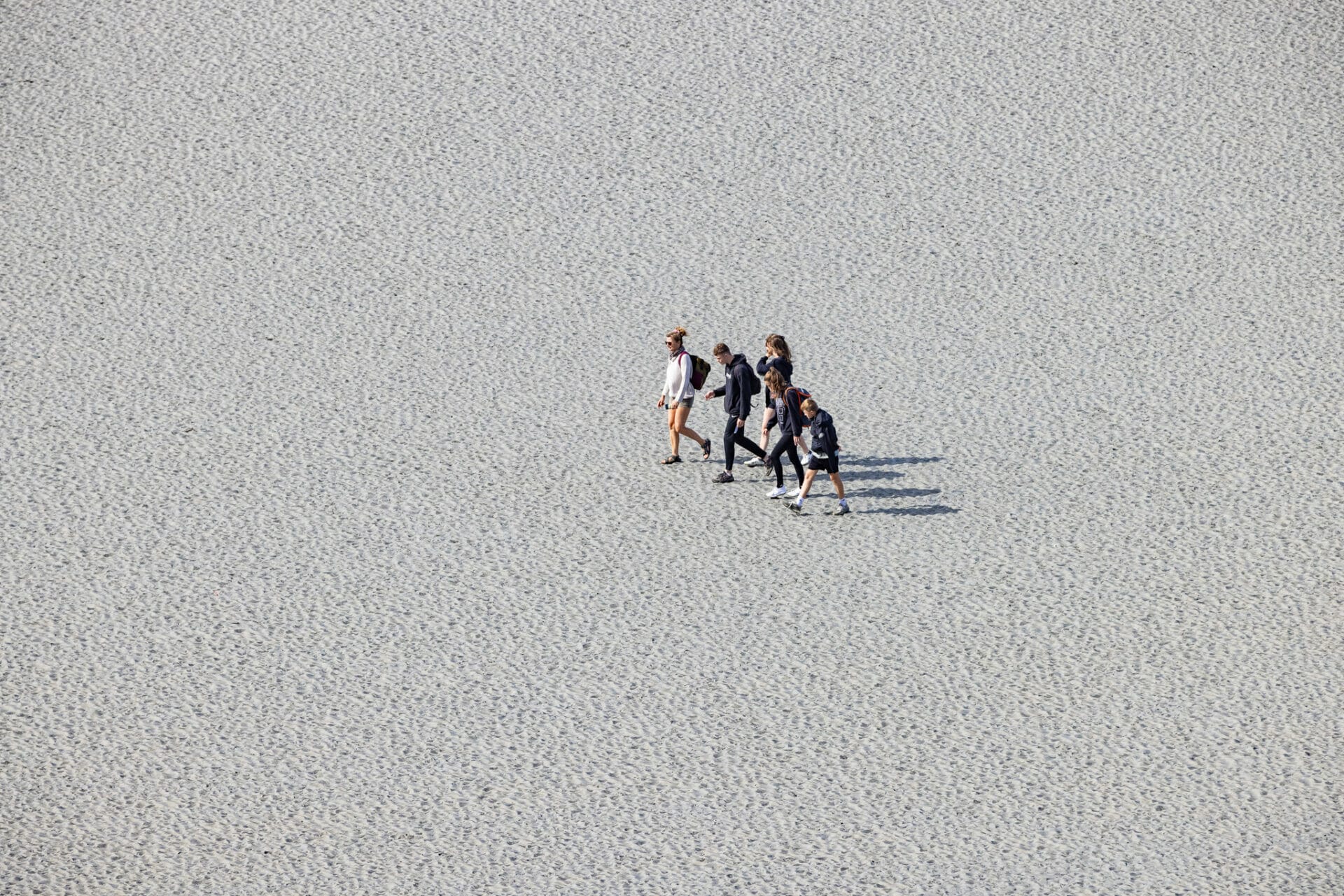 Modern pilgrims crossing the sandy tidal flats before Mont Saint-Michel
