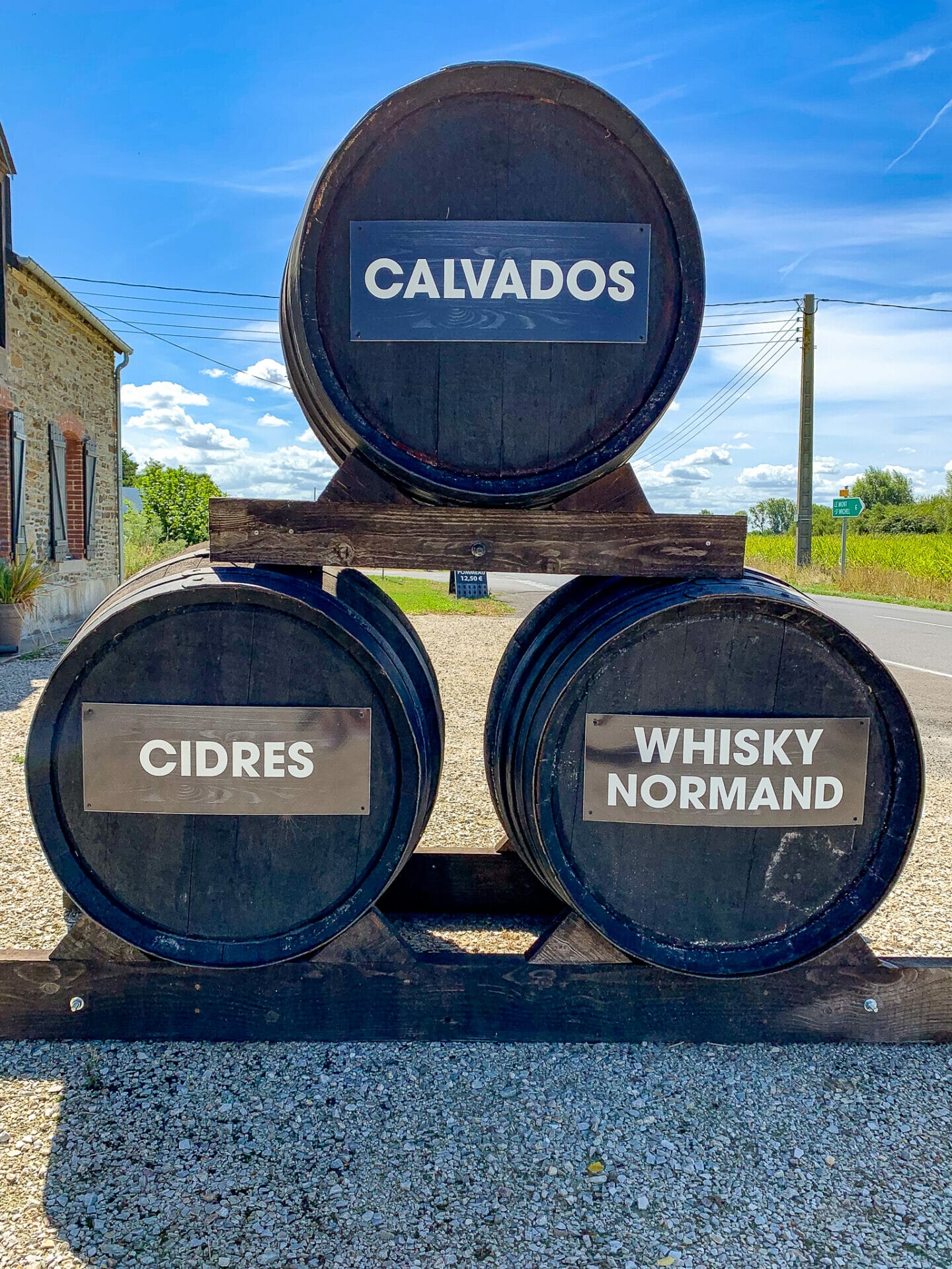 Piled wooden barrels with labels reading "Calvados","Cidres", "Whisky Normand", at Ferme d'Antan near Mont Saint-Michel