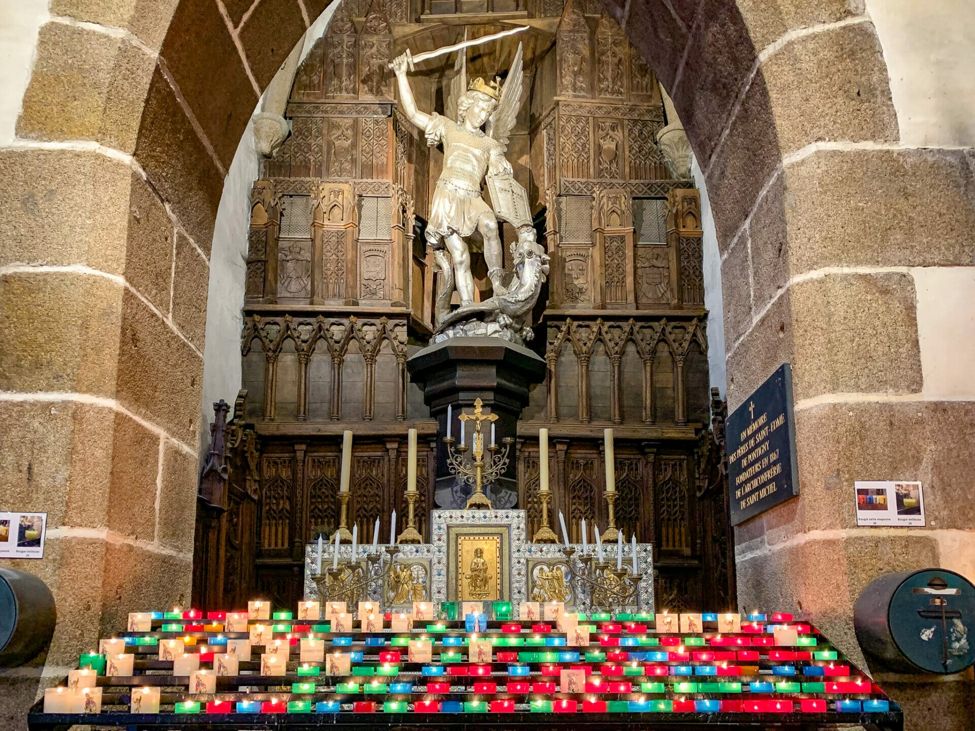 Best things to do in Mont Saint Michel, St. Michel statue behind votive candles in St Pierre Church 