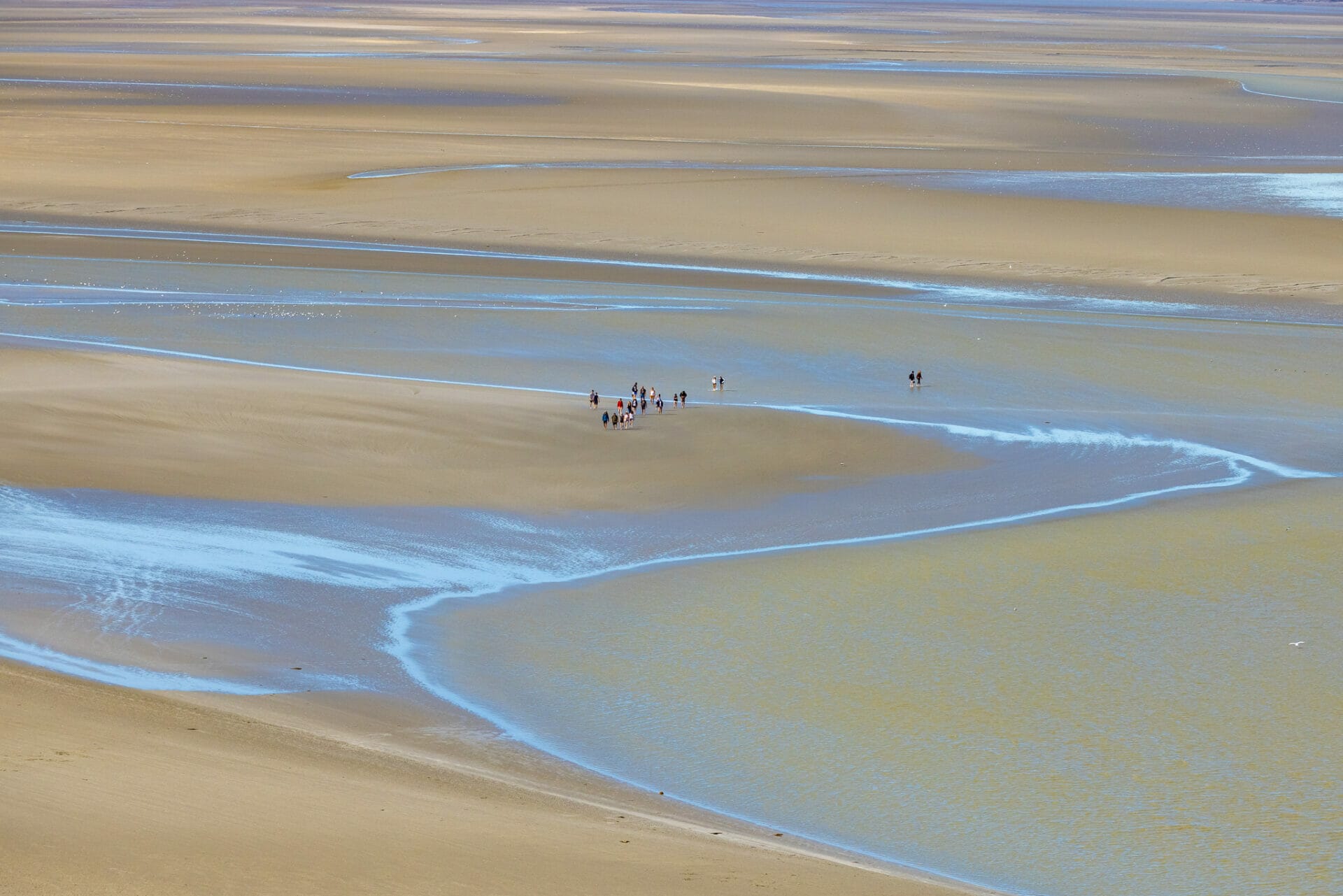 People on a guided tour crossing the sandy tidal flats at Mont Saint-Michel